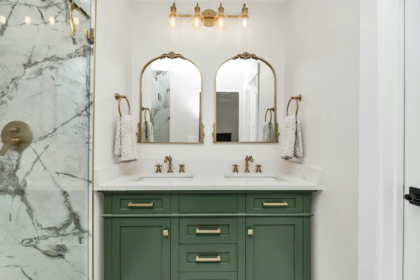 A bathroom with marble counter tops and green cabinets