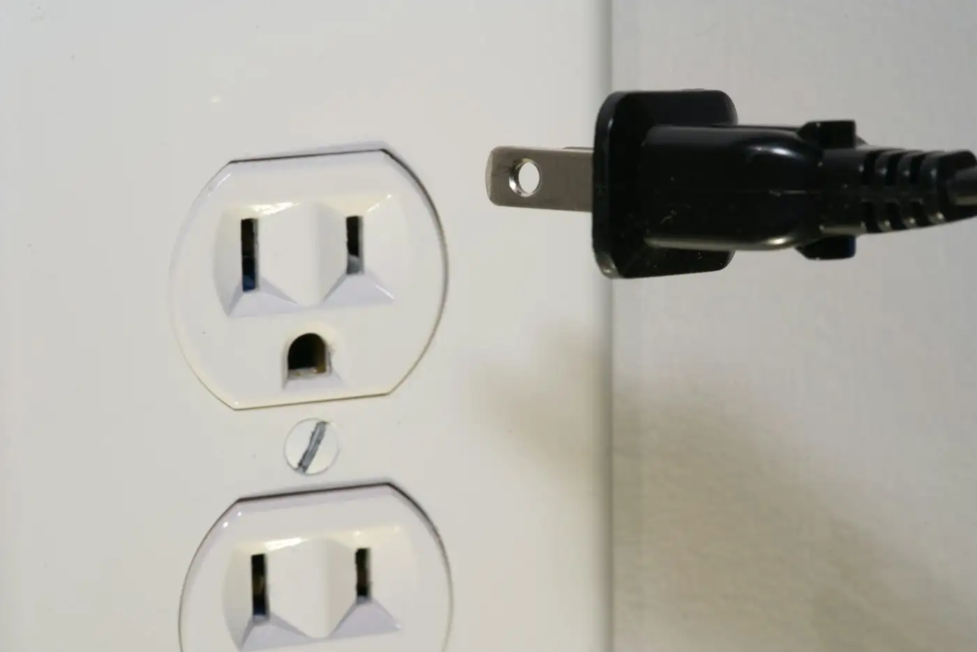 Black male plug in front of electric socket