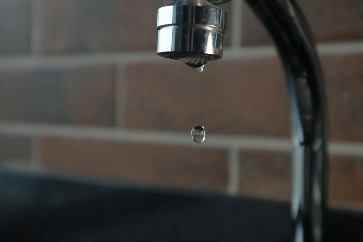 A faucet with a water drop hanging from it