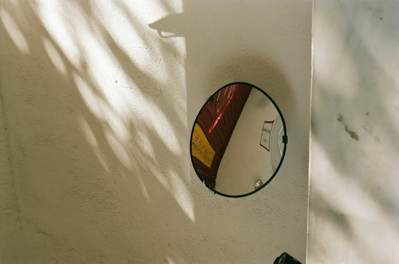 A white wall with a circular mirror on it
