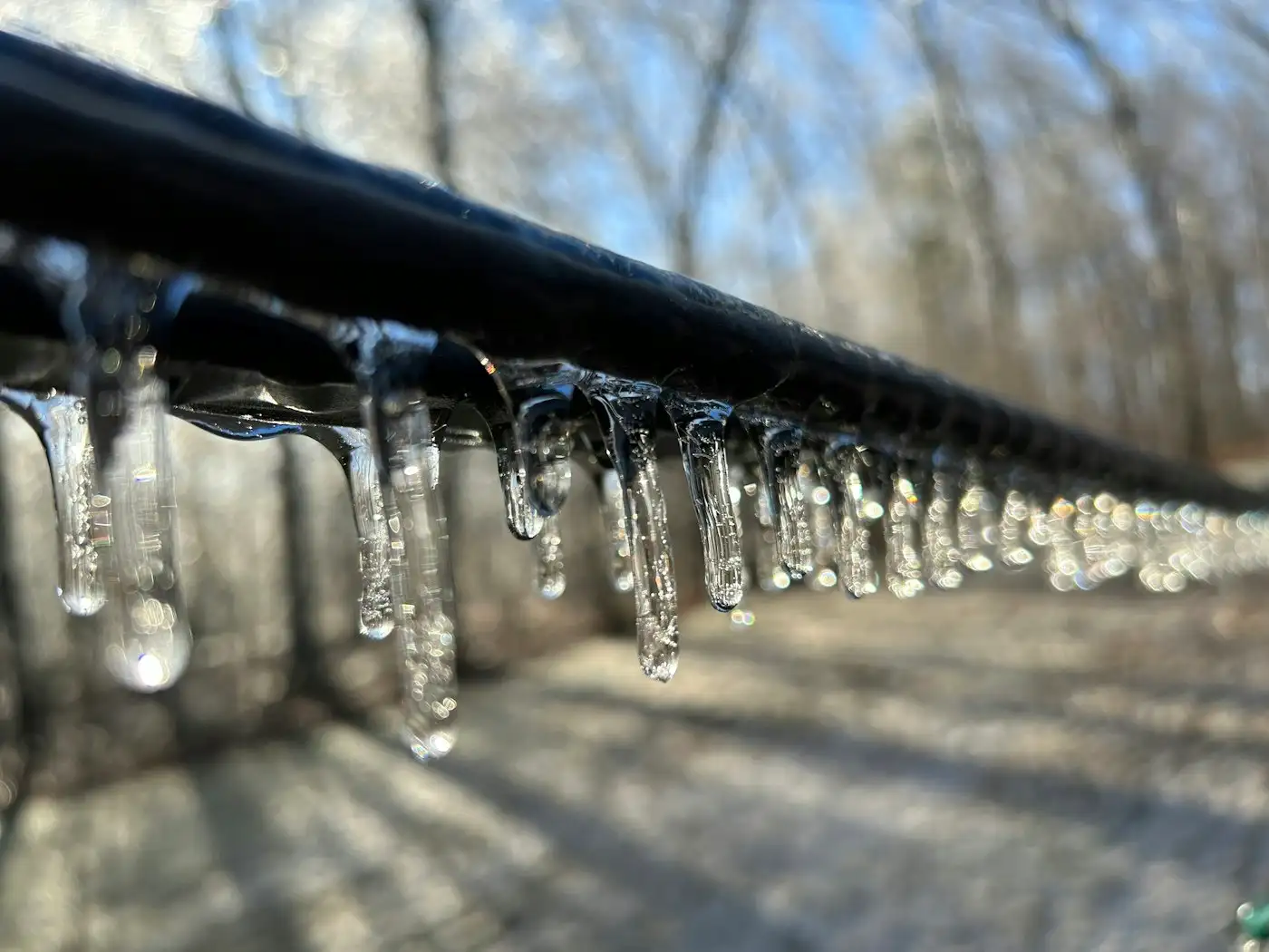 A line of water droplets hanging from a metal rail