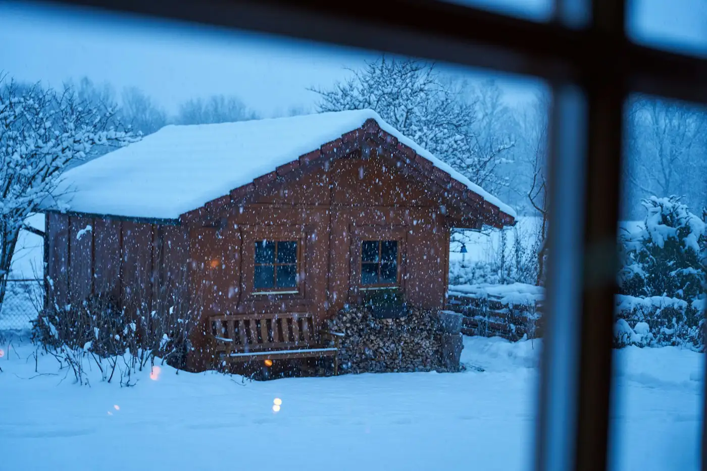 A cabin in the snow seen through a window