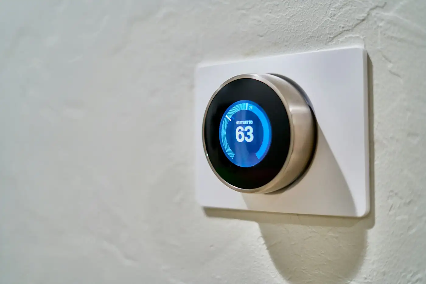 Gray nest thermostat displaying at 63