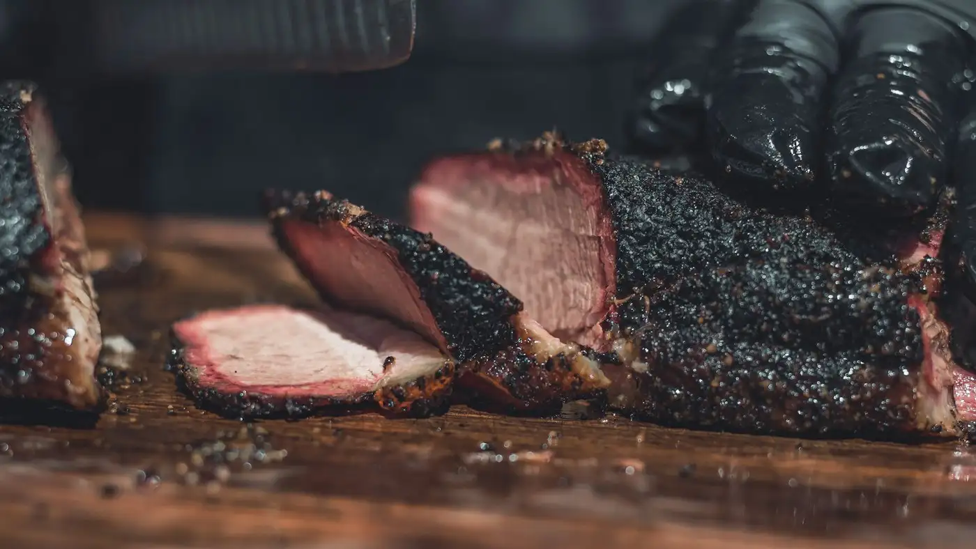 Sliced meat on brown wooden chopping board