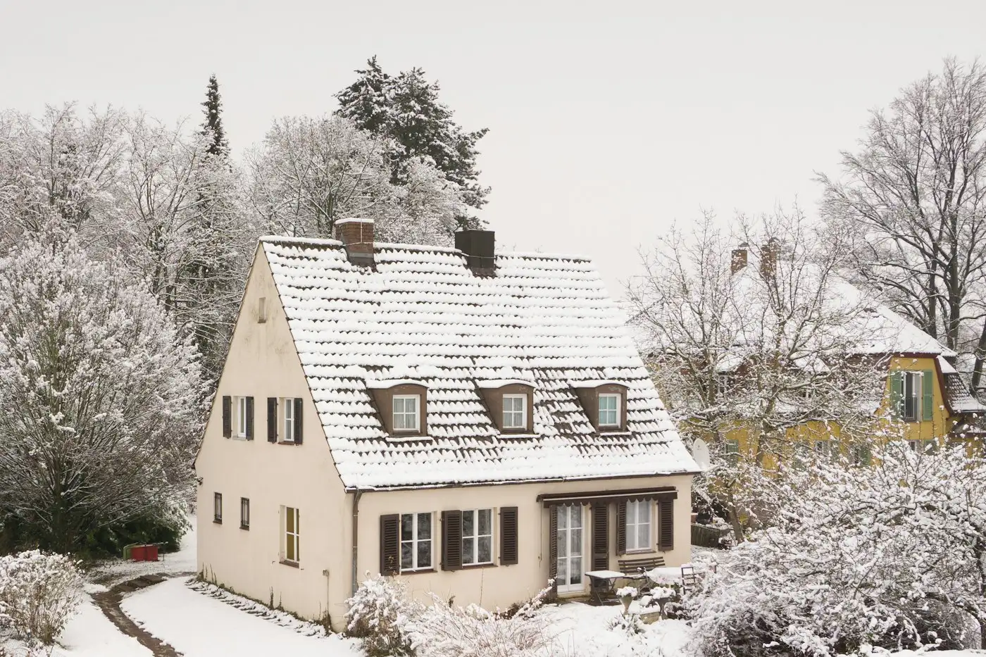 A house covered in snow next to trees